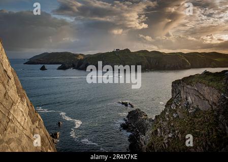 Blick auf die Fähre, die durch die Gewässer um Cape Clear auf Sherkin Island fährt, vom Dorf Baltimore bei Sonnenuntergang; West Cork, Irland Stockfoto