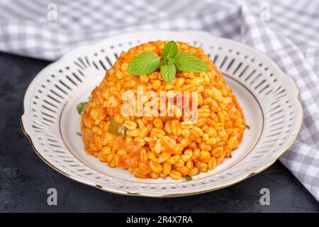 Traditioneller türkischer Bulgur-Pilaf mit Tomatensoße auf dem Teller (türkischer Name; Meyhane pilavi) Stockfoto