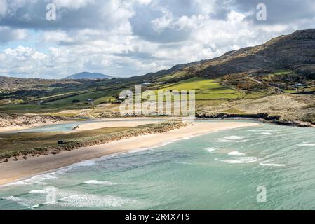 Malerischer Blick auf die türkisfarbenen Wellen des Atlantiks, die das Sandstrand von Barleycove mit den Hügeln und dem Ackerland der Landschaft bedecken... Stockfoto