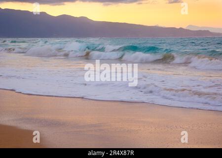 Nahaufnahme von schaumiger Brandung und türkisfarbenen Wellen, die an der Sandküste von Baldwin Beach an der Nordküste von Maui nahe Paia brechen, mit dem pastellfarbenen Lilien... Stockfoto