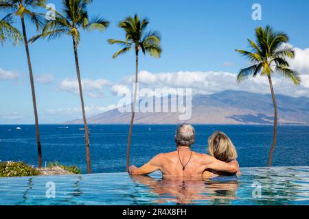 Blick von hinten auf ein Paar, das den Meerblick vom Infinity-Pool im Four Seasons Resort genießt Stockfoto