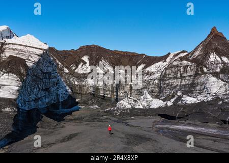 Frau, die durch die Landschaft in der Nähe eines Gletschers im Süden Islands läuft; Vik, Südisland, Island Stockfoto