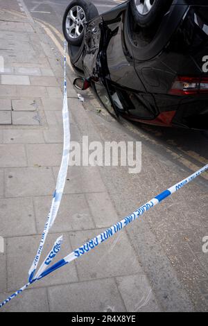 Das Polizeivideo umgibt die Folgen eines Autounfalls, bei dem ein umgestürzter Nissan-Heck an einer Bushaltestelle zwischen Brixton und Camberwell auf der Coldharbour Lane am 30. Mai 2023 in London, England, bleibt. Stockfoto