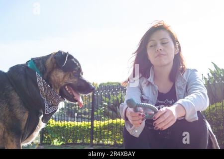 Junge latina-Frau aus kolumbien sitzt verärgert im Park, weil ihr Hund sie ignoriert, Haustierkonzept, Kopierraum. Stockfoto
