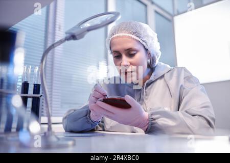 Wissenschaftlerin, die Petrischale hält, während sie Bioforschung im Labor durchführt Stockfoto