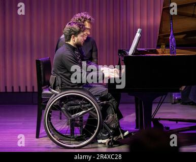 Ein körperlicher Konzertpianist spielt mit einem anderen Pianisten, der eine Rückenmarksverletzung hat: Edmonton, Alberta, Kanada Stockfoto