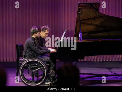 Ein körperlicher Konzertpianist spielt mit einem anderen Pianisten, der eine Rückenmarksverletzung hat: Edmonton, Alberta, Kanada Stockfoto