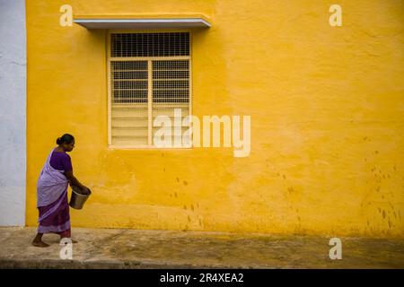 Frau bewässert einen unbefestigten Bürgersteig in Indien; Puducherry, Tamil Nadu, Indien Stockfoto