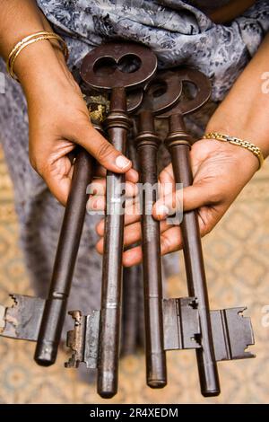 Frau hält große Schlüssel zu einem Herrenhaus in Indien aus; Chettinad, Tamil Nadu, Indien Stockfoto