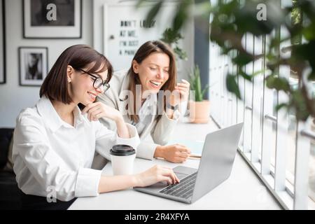 Teamarbeit und Einheit. Zwei junge Spezialisten arbeiten zusammen an einem Laptop und diskutieren Ideen im Büro Stockfoto