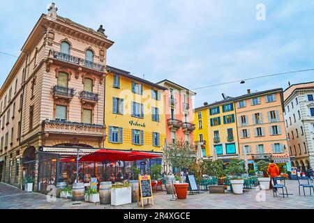 LUGANO, SCHWEIZ - 14. MÄRZ 2022: Die Piazza della Riforma ist berühmt für ihre wunderschönen alten Stadthäuser und gemütlichen Restaurants mit Außenterrassen, Stockfoto