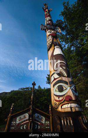 Totempfahl und Clan House im Totem Bight State Park, Ketchikan, Alaska, USA; Ketchikan, Alaska, Vereinigte Staaten von Amerika Stockfoto