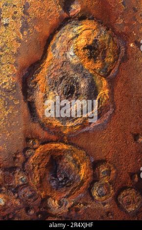 Leuchtende, lebendige Farben, die durch das Rosten der alten Stahlplatten eines Schiffes an einem Strand in Cornwall entstanden sind. Stockfoto