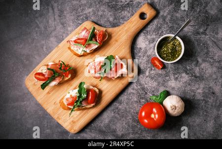 Bruschetta mit Prosciutto, Pesto, Mozzarella und Tomaten. Speisen-, Restaurant- und Veranstaltungskonzept. Stockfoto