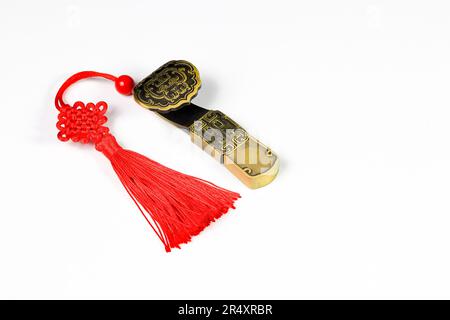 Traditionelles chinesisches Messingamulett als Geschenk. Chinesisches Amulett mit roten dekorativen Glücksknoten bedeutet Glück, Glück und reich auf Weiß Stockfoto