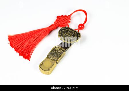 Traditionelles chinesisches Messingamulett als Geschenk. Chinesisches Amulett mit roten dekorativen Glücksknoten bedeutet Glück, Glück und reich auf Weiß Stockfoto