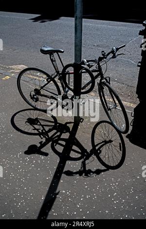 Das Fahrrad wirft seinen Schatten auf den Bürgersteig in Edinburgh, Schottland, Großbritannien. Stockfoto