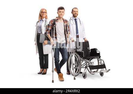 Verletzter männlicher Student mit Krücken, die bei Ärzten stehen, isoliert auf weißem Hintergrund Stockfoto