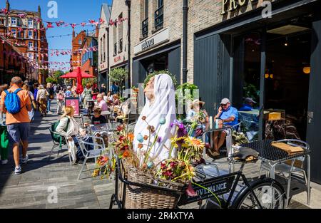 An einem sonnigen Tag während der Chelsea Flower Show gibt es in der Symons Street im Sloane Square SW3 in London eine lebhafte Cafékultur und Restaurants am Straßenrand Stockfoto