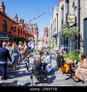 An einem sonnigen Tag während der Chelsea Flower Show gibt es in der Symons Street im Sloane Square SW3 in London eine lebhafte Cafékultur und Restaurants am Straßenrand Stockfoto