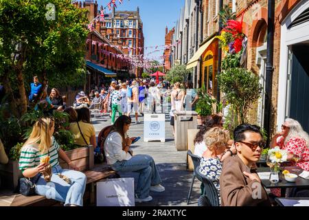 An einem sonnigen Tag während der Chelsea Flower Show gibt es in der Symons Street im Sloane Square SW3 in London eine lebhafte Cafékultur und Restaurants am Straßenrand Stockfoto