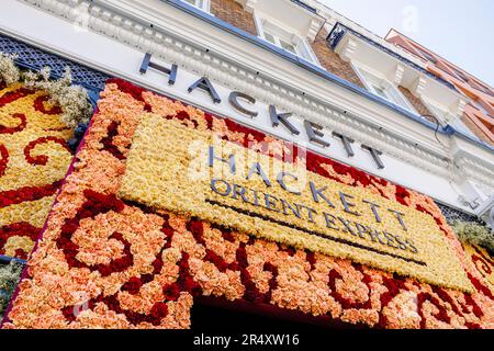 Eine Blumenausstellung am Eingang des Hackett Shop in der Sloane Street in der Nähe des Sloane Square in Chelsea in Bloom während der Chelsea Flower Show, London SW3 Stockfoto