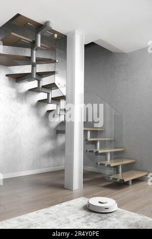 Eine Treppe mit hölzernen Stufen und einem eleganten Glaszaun, eine Säule aus mattem Glas, große Innenblume im modernen Interieur des Apartments. Stockfoto