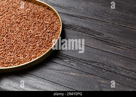 Schokoladenstücke in einer runden Schachtel auf dunklem Holzhintergrund, Kopierraum. Das Konzept von Süßwaren, Schokoladenherstellung. Stockfoto
