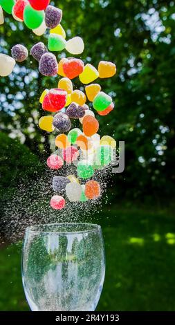 Farbenfrohe Süßigkeiten, die aus Glas im Freien herausfliegen Stockfoto