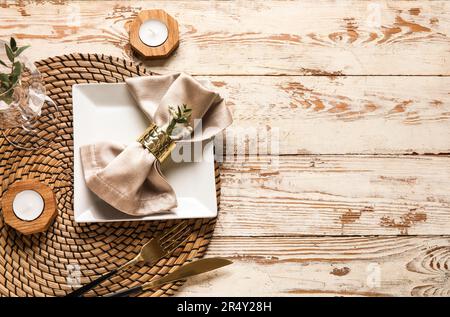 Schöne Tischgestaltung mit Kerzen und Zigeunerblumen auf hellem Holzhintergrund Stockfoto