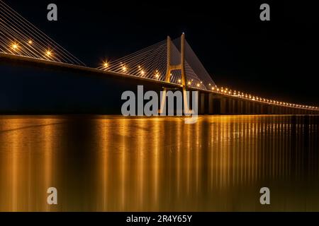 Goldene Reflexionen auf der Vasco da Gama Brücke bei Nacht Stockfoto