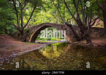 Kelefos mittelalterliche Brücke auf Zypern. Eine alte venezianische Steinbrücke Tzelefos spiegelt sich im Fluss wider. Stockfoto