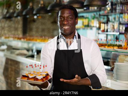 Ein Blick auf den erwachsenen afrikanischen Mann mit Pinchos in einer Bar Stockfoto