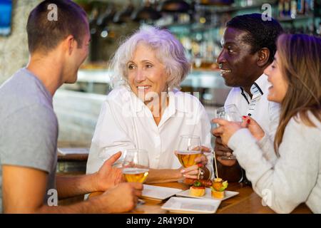 Eine freundliche, fröhliche Familie, die ein Treffen mit Gläsern und Bier in der Bar feiert. Hauptfokus genau in der Mitte Stockfoto