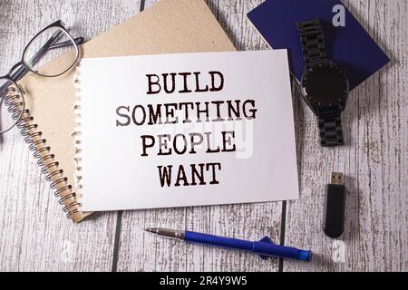 Baue etwas, das die Leute wollen.Text auf weißem Notizblock auf Kunsthandwerk-Hintergrund Stockfoto