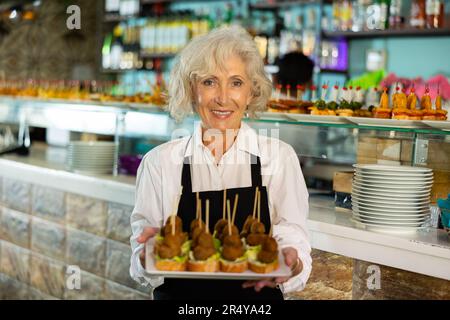 VIW über die europäische alte Dame, die Tapas in einem Pub hält Stockfoto
