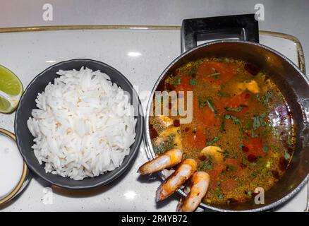 Tom Yam, Tom yan, Tom Yum mit Garnelen, Chili, Pilzen, Tomaten, Limette und Reis auf einem Tablett Stockfoto