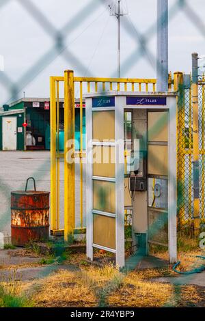 Telefonzelle im alten Stil hinter einem Kettenanschlusszaun in Steveston, British Columbia, Kanada Stockfoto