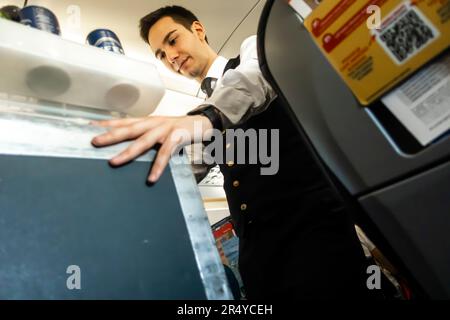 Flugbegleiter serviert Mahlzeiten und Getränke für Passagiere, die in einem Stuhl in einer Flugzeugkabine sitzen Airbus pegasus Airbus A 320 Stockfoto