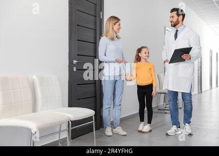 Arzt mit Klipboard als beratende Mutter und Tochter in der Klinik Stockfoto