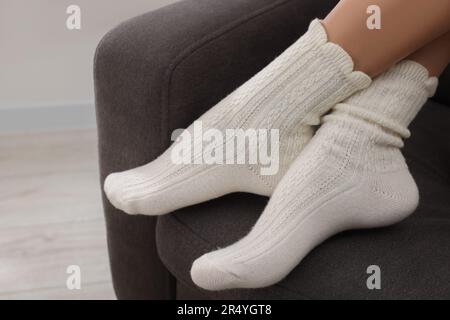 Eine Frau in warmen Socken, die sich zu Hause auf dem Sessel entspannt Stockfoto