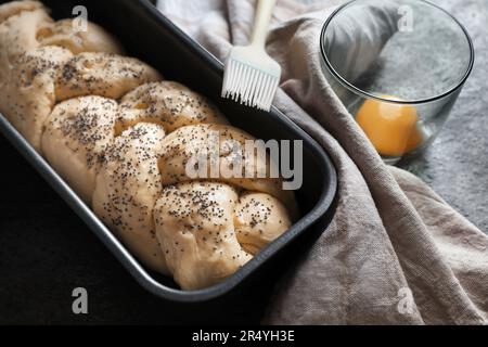 Hausgemachtes geflochtenes Brot und Zutaten auf grauem Tisch. Traditionelle Sabbat-Challah-Küche Stockfoto