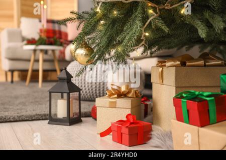 Geschenkschachteln unter Weihnachtsbaum und Laterne mit Kerze drinnen Stockfoto