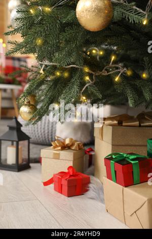 Geschenkschachteln unter Weihnachtsbaum und Laterne mit Kerze drinnen Stockfoto