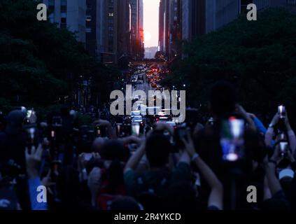 New York, Usa. 30. Mai 2023. Feierliche und Fotografen machen am Dienstag, den 30. Mai 2023, Fotos von einem Ereignis bei Sonnenuntergang in Manhattan mit Blick auf den Sonnenuntergang von der 42. Street in New York City. Der Sonnenuntergang über Manhattan findet zweimal im Jahr statt, wenn die untergehende Sonne genau auf Manhattans Straßennetz ausgerichtet ist. Foto: John Angelillo/UPI Credit: UPI/Alamy Live News Stockfoto