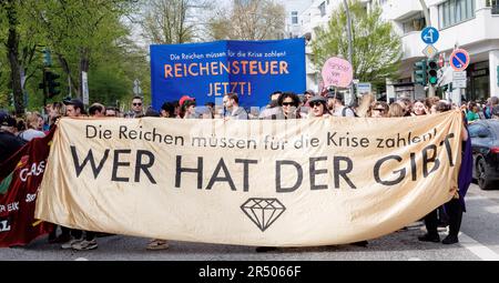 Hamburg, Deutschland. 02. Mai 2023. Demonstranten bei einer Maifeier-Rallye tragen Banner mit der Aufschrift "die Reichen müssen für die Krise bezahlen! Die Steuer ist hoch! ' Und ' Wer gibt '. Kredit: Markus Scholz/dpa/Alamy Live News Stockfoto