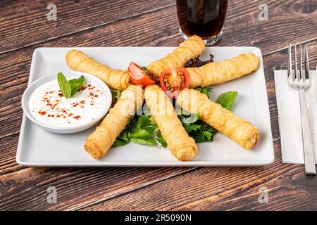 Türkische Zigarrenrollen auf einer weißen Porzellanplatte. Der türkische Name ist Sigara Boregi Stockfoto