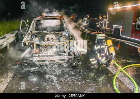 Pforzheim, Deutschland. 31. Mai 2023. Feuerwehrleute löschen einen ausgebrannten Pkw auf der Autobahn A8 in der Nähe von Pforzheim. Das Auto fuhr von Nacht bis Mittwoch in Richtung Stuttgart, als die drei Insassen eine Rauchentwicklung aufgrund eines technischen Defekts bemerkten, wie ein Polizeisprecher sagte. Dementsprechend parkten sie das Auto auf dem harten Schulter. Kurz darauf brannte es in Flammen auf. Der Schaden beträgt etwa 90.000 Euro. Alle Insassen blieben unverletzt. Kredit: Markus Rott/Einsatz-Report24/dpa/Alamy Live News Stockfoto