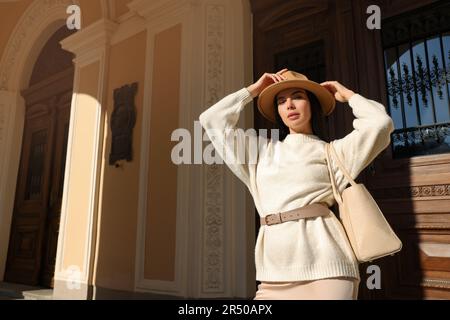 Junge Frau mit stilvoller Tasche vor dem wunderschönen Gebäude, niedriger Blickwinkel. Platz für Text Stockfoto