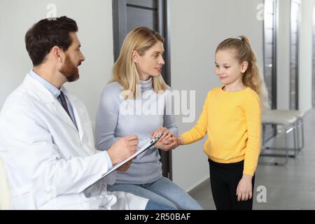Arzt mit Klipboard als beratende Mutter und Tochter in der Klinik Stockfoto